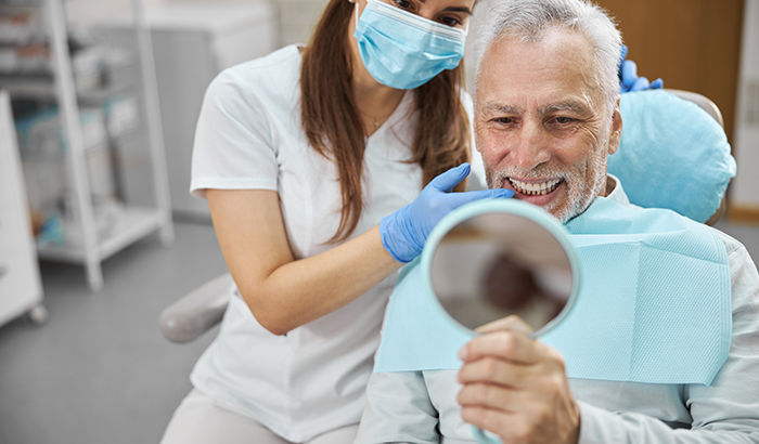Older man looking at his new dental implants at Lincoln Center Smiles in Portland, OR